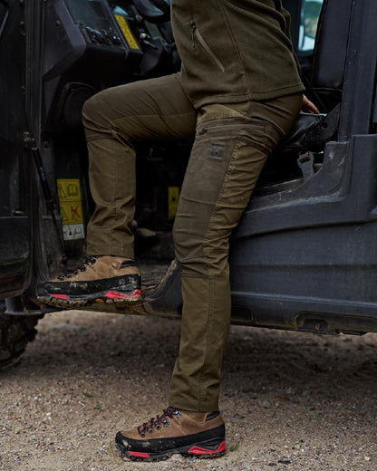 Dark Olive Willow Green Coloured Harkila Womens Fjell Trousers on tractor background #colour_dark-olive-willow-green