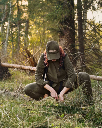 Willow Green Coloured Harkila Womens Herlet Tech Shirt on forest background #colour_willow-green