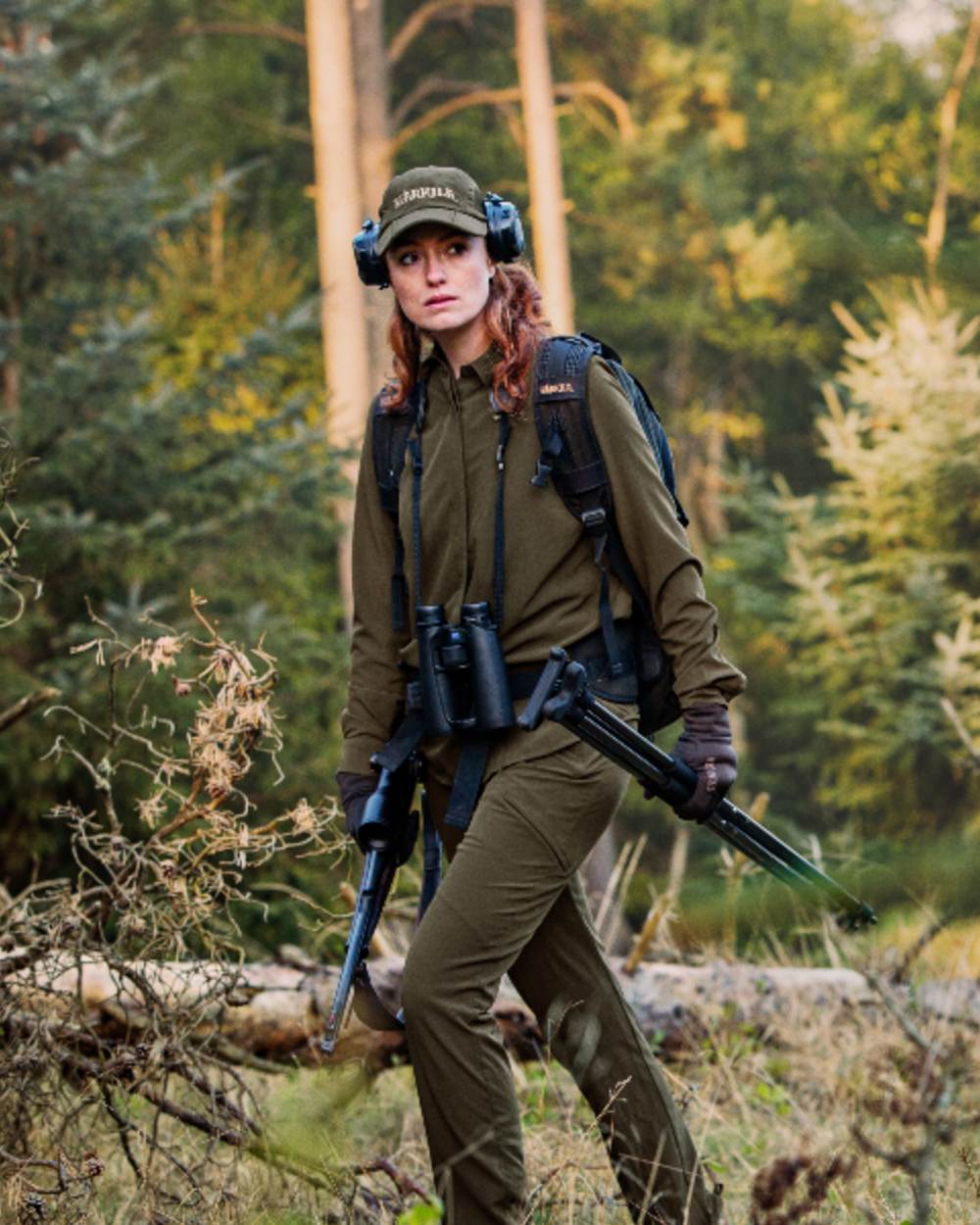 Willow Green Coloured Harkila Womens Herlet Tech Shirt on forest background #colour_willow-green