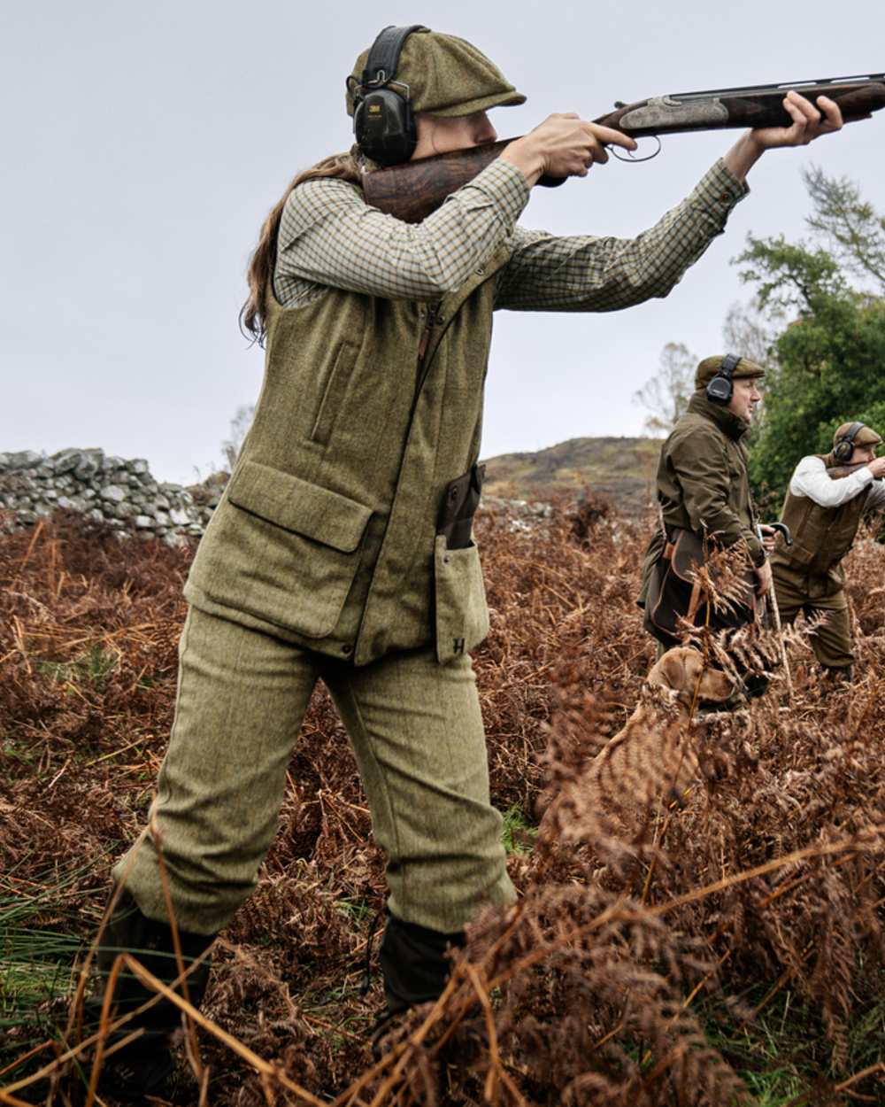 Olive Coloured Harkila Womens Jura Waistcoat on forest background #colour_olive