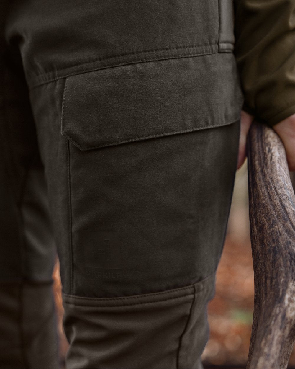 Shadow Brown Deep Brown coloured Harkila Womens Scandinavian Trousers on woodland background #colour_shadow-brown-deep-brown