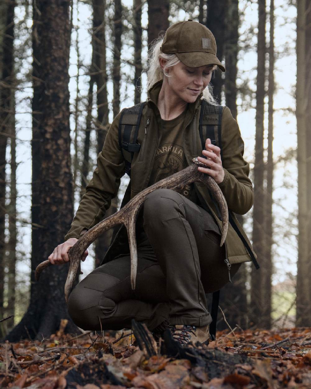 Shadow Brown Deep Brown coloured Harkila Womens Scandinavian Trousers on woodland background #colour_shadow-brown-deep-brown