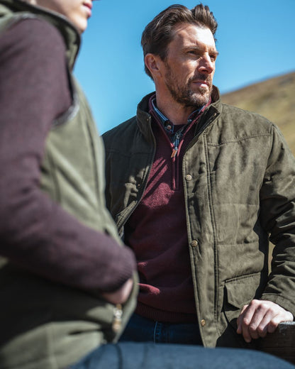 Loden coloured Hoggs of Fife Mens Glenesk Quilted Jacket on blurry background #colour_loden