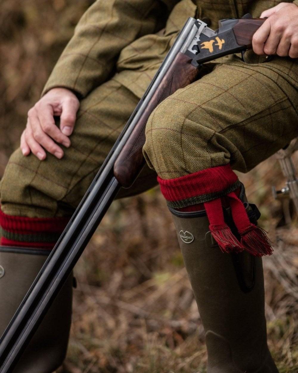 Brick Red Spruce coloured House of Cheviot Estate Field Socks on blurry background #colour_brick-red-spruce