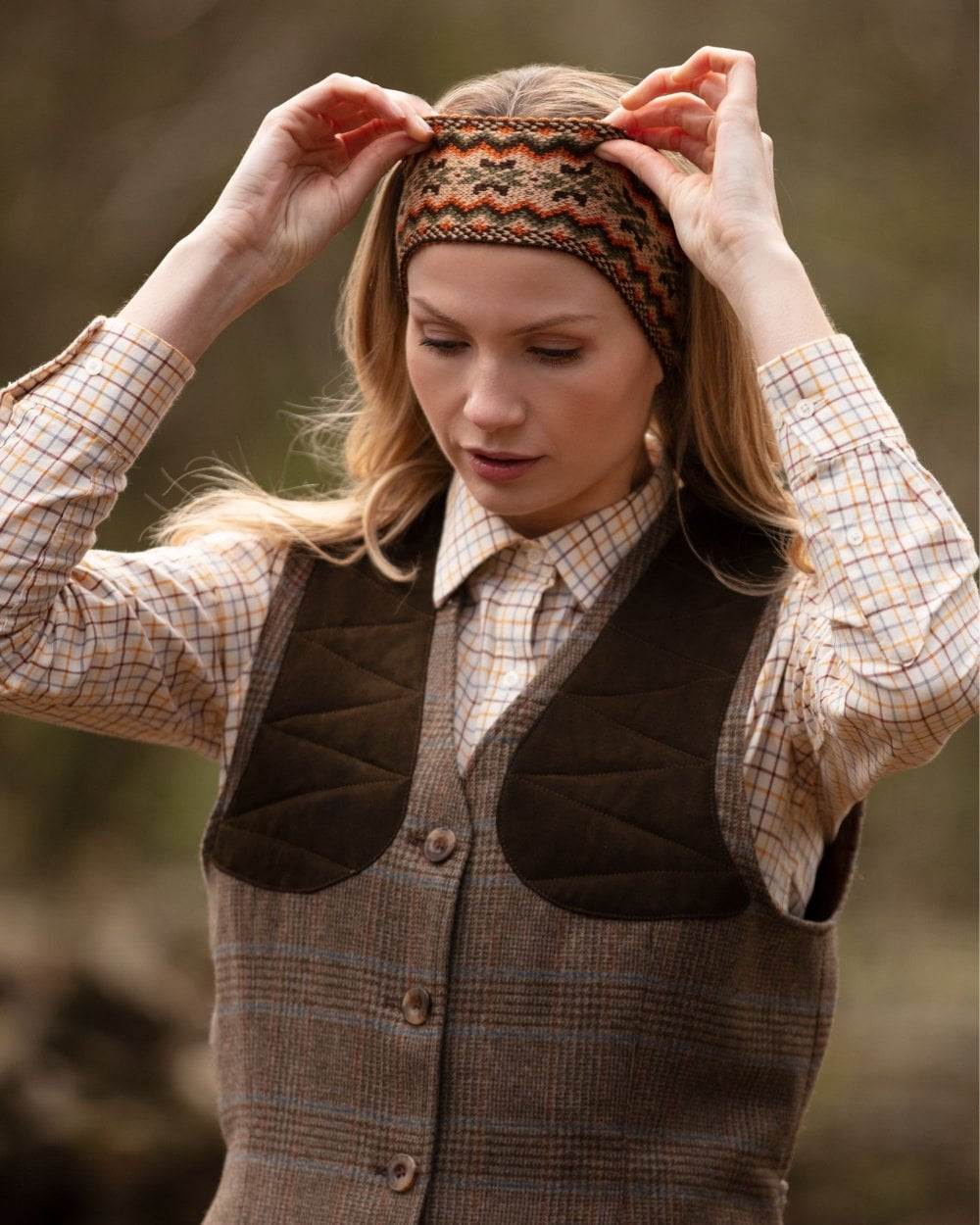 Dark Olive coloured House of Cheviot Lady Fairisle Headband on blurry background #colour_dark-olive