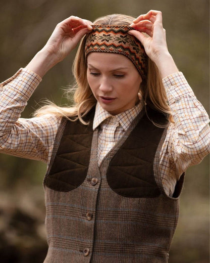 Dark Olive coloured House of Cheviot Lady Fairisle Headband on blurry background #colour_dark-olive
