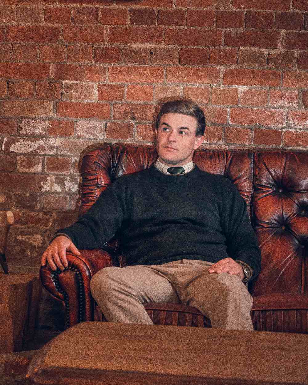 Dark Olive coloured Jack Pyke Ashcombe Lambswool Crewknit Pullover on brick wall background #colour_dark-olive