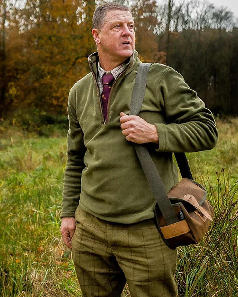 Dark Olive coloured Jack Pyke Countryman Fleece Pullover on forest background #colour_dark-olive