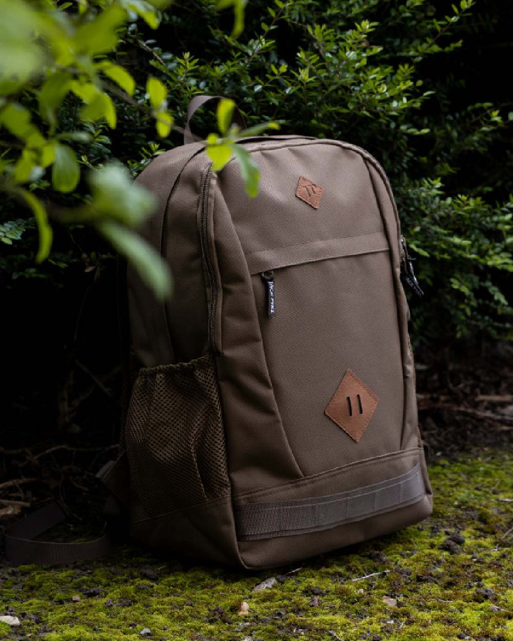Olive Brown coloured Jack Pyke Falcon Rucksack on leafy background #colour_olive-brown
