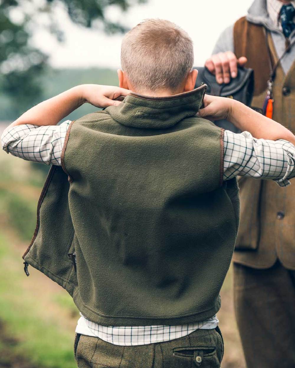 Dark Olive coloured Jack Pyke Junior Countryman Gilet on blurry background #colour_dark-olive