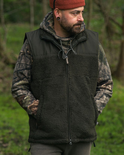 Dark Olive coloured Jack Pyke Sherpa Fleece Gilet on forest background #colour_dark-olive