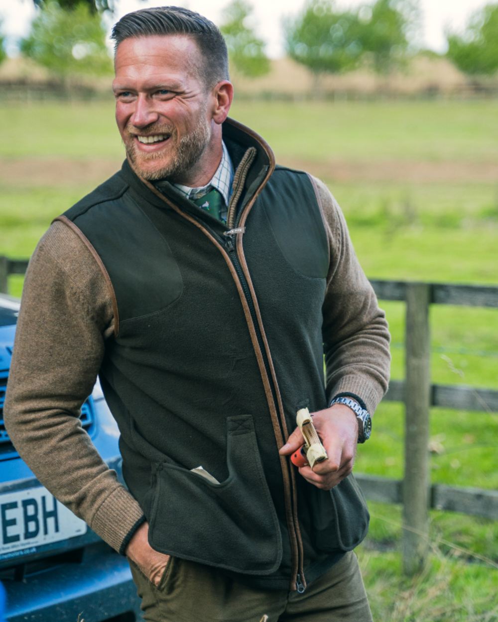 Dark Olive Jack Pyke Shooters Gilet on forest background #colour_dark-olive