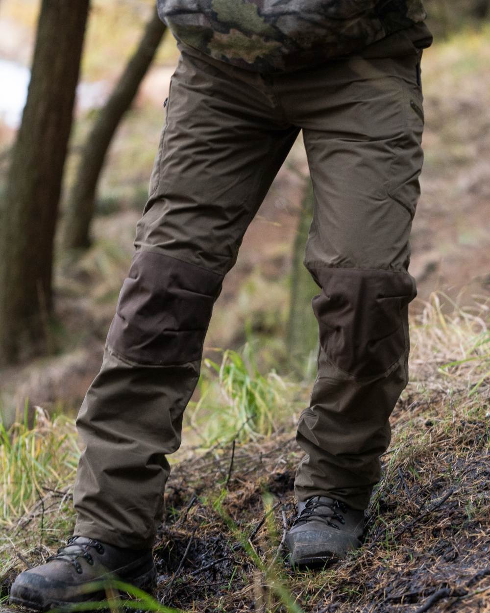 Brown coloured Jack Pyke Weardale Hunting Trousers on forest background #colour_brown