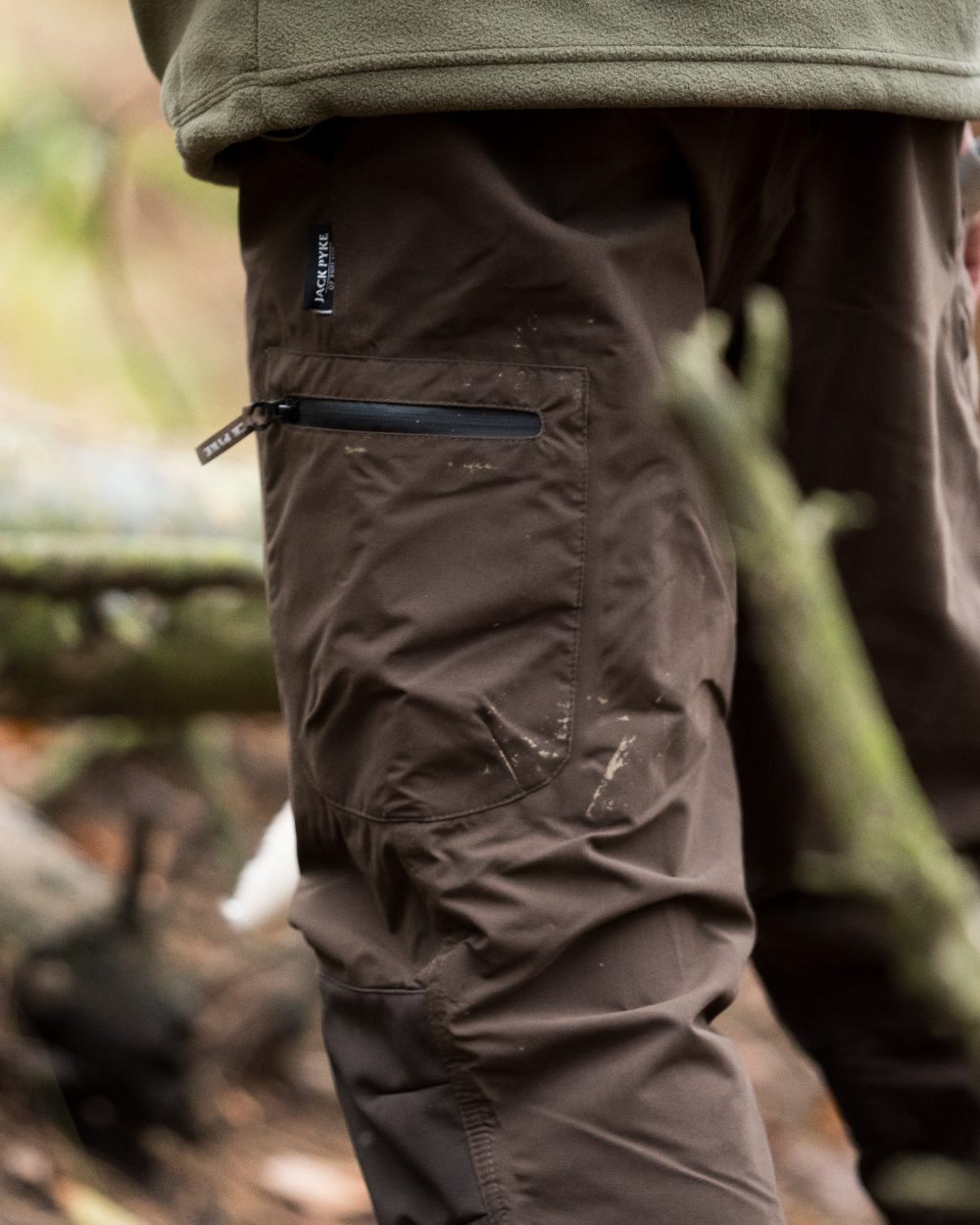 Brown coloured Jack Pyke Weardale Hunting Trousers on forest background #colour_brown
