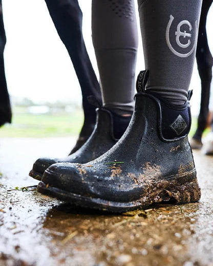 Black Coloured Muck Boots Wear Ankle Boots on ground background #colour_black