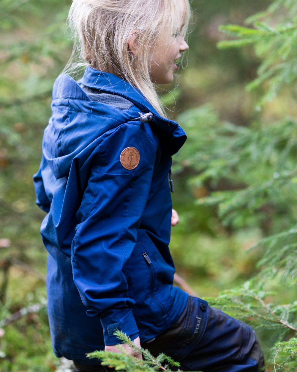 Dark Dive coloured Pinewood Childrens Finnveden Hybrid Jacket on forest background #colour_dark-dive