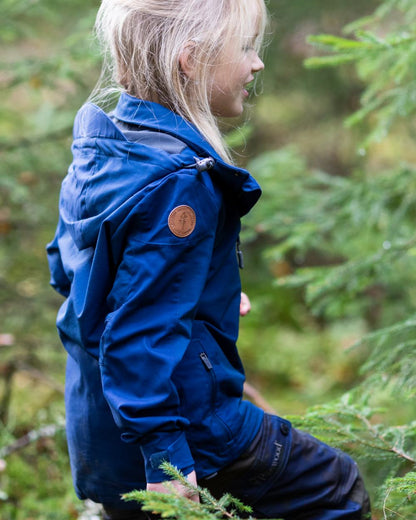 Dark Dive coloured Pinewood Childrens Finnveden Hybrid Jacket on forest background #colour_dark-dive