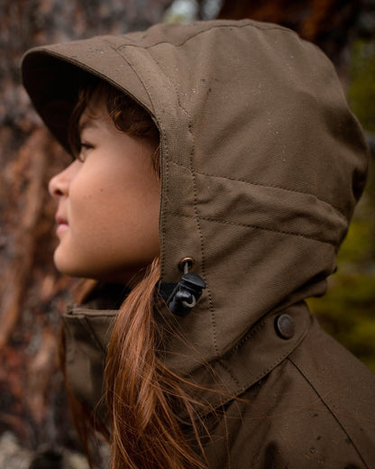 Hunting Olive coloured Pinewood Childrens Finnveden Hybrid Jacket on forest background #colour_hunting-olive