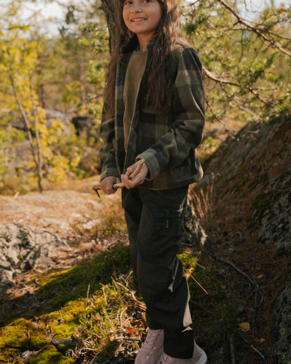 Black coloured Pinewood Childrens Lappland Trousers on forest background #colour_black