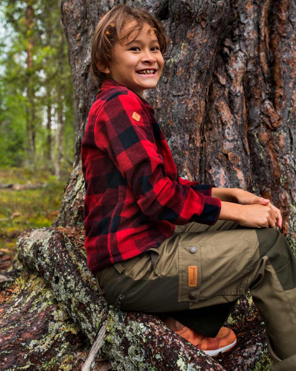 Olive Moss Green coloured Pinewood Childrens Lappland Trousers on forest background #colour_olive-moss-green