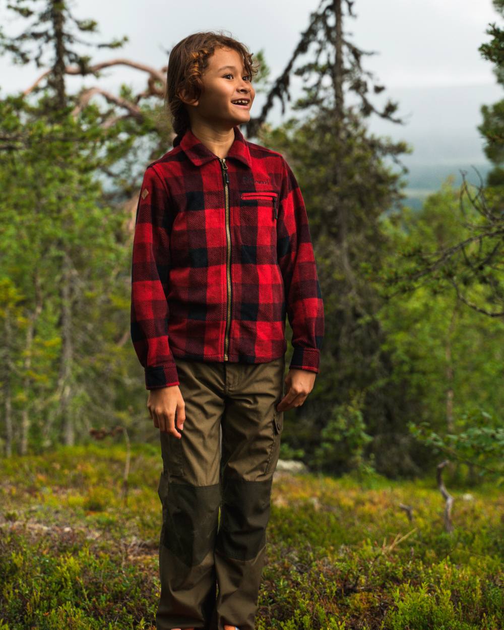 Olive Moss Green coloured Pinewood Childrens Lappland Trousers on forest background #colour_olive-moss-green