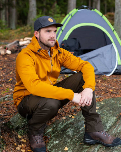 Dark Olive Suede Brown Coloured Pinewood Mens Abisko Brenton Trousers on forest background #colour_dark-olive-suede-brown