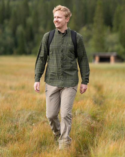 Moss Green Coloured Pinewood Mens Abisko Trekking Long Sleeve Shirt on outdoor background #colour_moss-green
