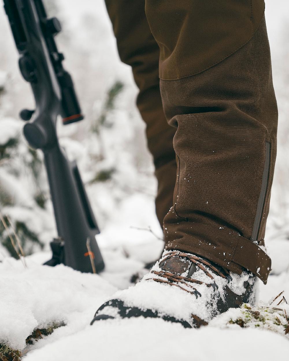 Suede Brown Dark Olive Coloured Pinewood Mens Caribou Hunt Extreme Trousers on snow background #colour_suede-brown-dark-olive