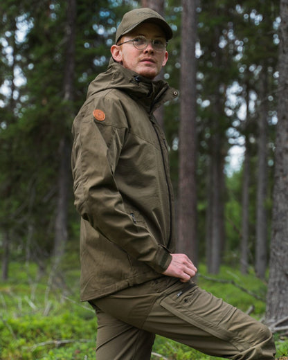 Hunting Olive Coloured Pinewood Mens Finnveden Hybrid Jacket on forest background #colour_hunting-olive