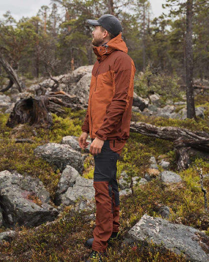 Terracotta coloured Pinewood Mens Finnveden Hybrid Jacket on forest background #colour_terracotta