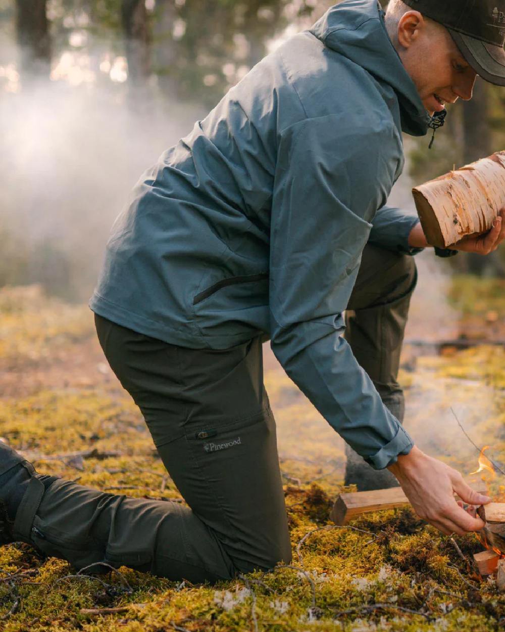 Dark Green coloured Pinewood Mens Finnveden Trail Stretch Trousers on forest background #colour_dark-green