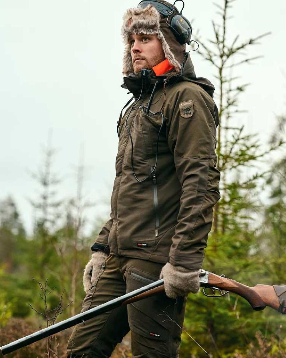 Moss Green coloured Pinewood Mens Hunter Pro Extreme 2.0 Jacket on forest background #colour_moss-green