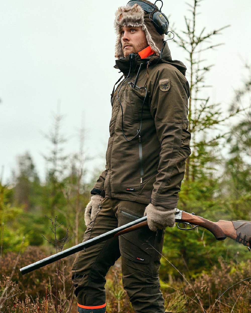 Moss Green coloured Pinewood Mens Hunter Pro Extreme 2.0 Trousers on forest background #colour_moss-green