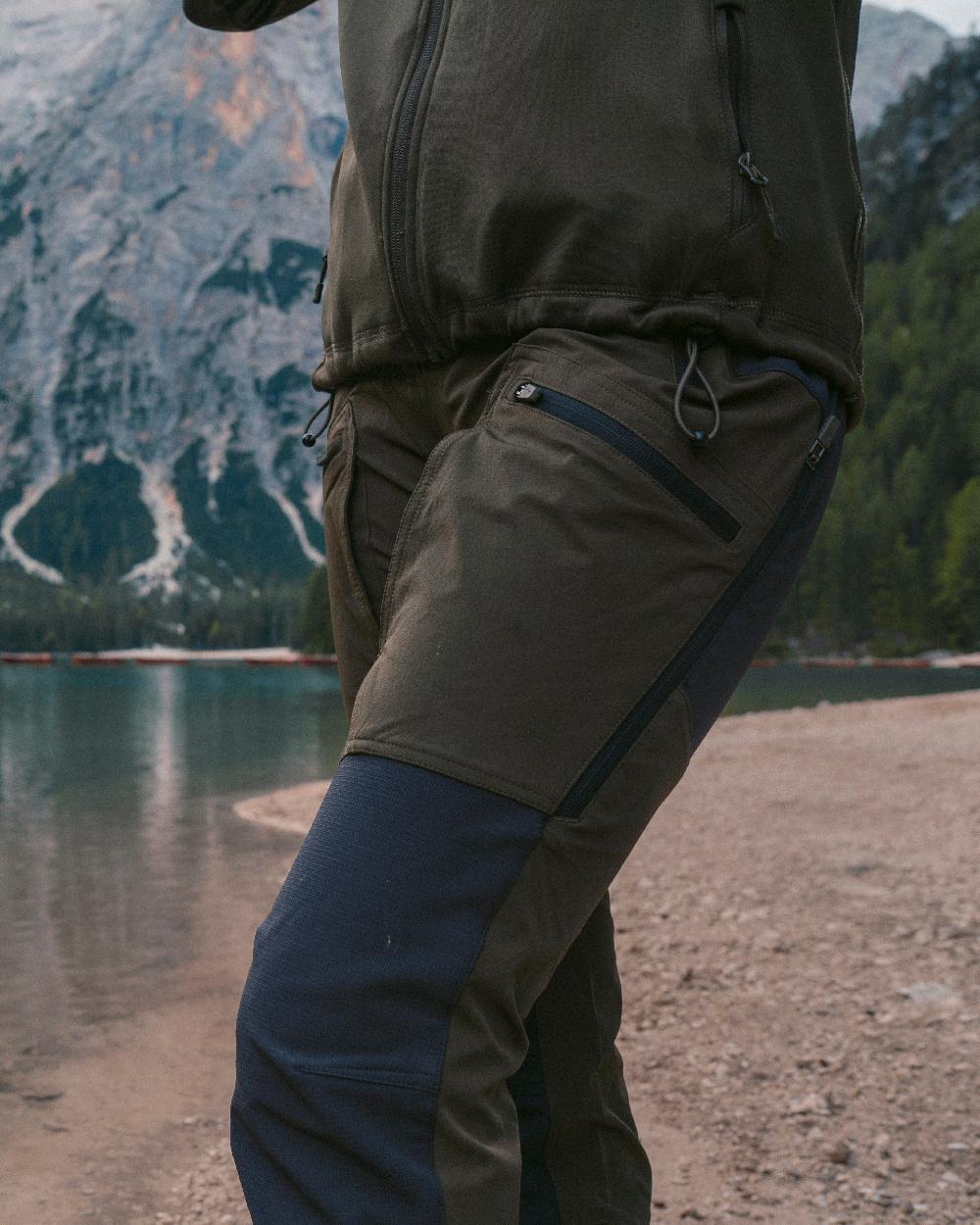 Moss Green Coloured Pinewood Womens Abisko Adventure Trousers on mountain background #colour_moss-green