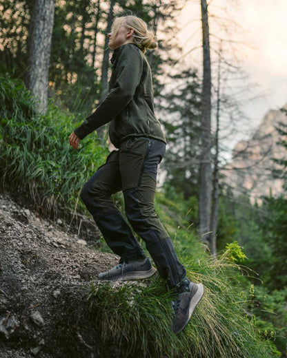 Moss Green Coloured Pinewood Womens Abisko Adventure Trousers on mountain background #colour_moss-green