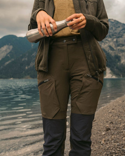 Moss Green Coloured Pinewood Womens Abisko Adventure Trousers on mountain background #colour_moss-green