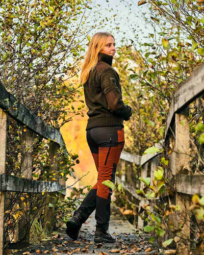 Terracotta Dark Anthracite Coloured Pinewood Womens Abisko Brenton Trousers on forest background #colour_terracotta-dark-anthracite