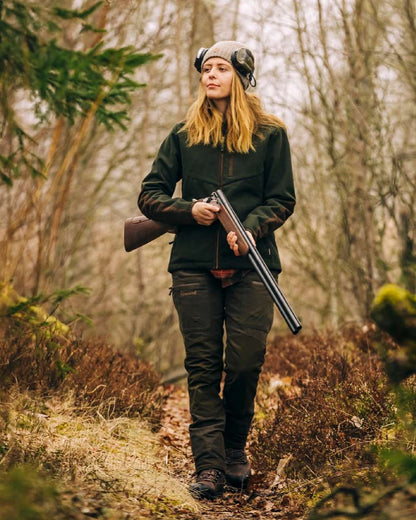 Suede Brown Dark Olive Coloured Pinewood Womens Furudal Caribou Hunt Trousers on forest background #colour_suede-brown-dark-olive