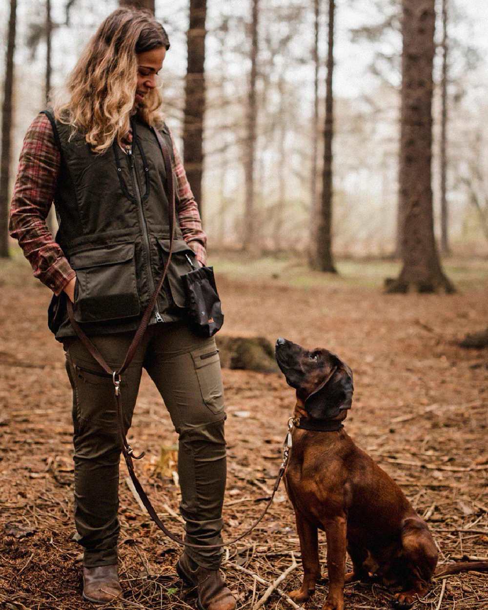 Black Moss Green coloured Pinewood Womens Dog Sports 2.0 Vest on forest background #colour_moss-green