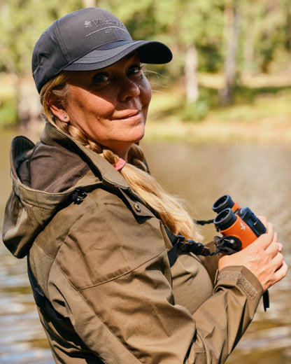 Hunting Olive Coloured Pinewood Womens Finnveden Hybrid Jacket on forest background #colour_hunting-olive