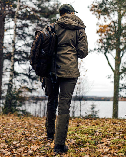 Hunting Olive Coloured Pinewood Womens Finnveden Hybrid Jacket on forest background #colour_hunting-olive