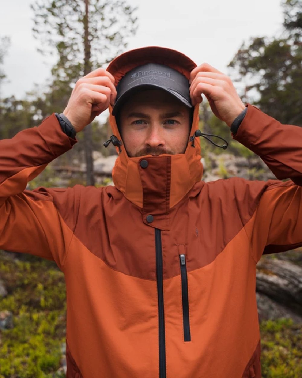 Terracotta coloured Pinewood Mens Finnveden Hybrid Jacket on forest background #colour_terracotta