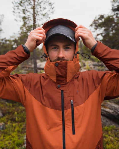 Terracotta coloured Pinewood Mens Finnveden Hybrid Jacket on forest background #colour_terracotta