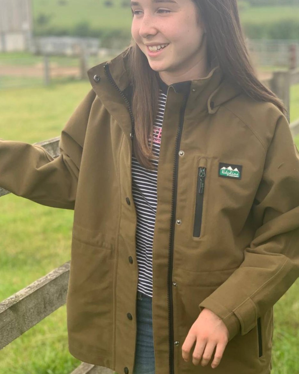 Teak coloured Ridgeline Kids Monsoon Classic Jacket on farm background #colour_teak