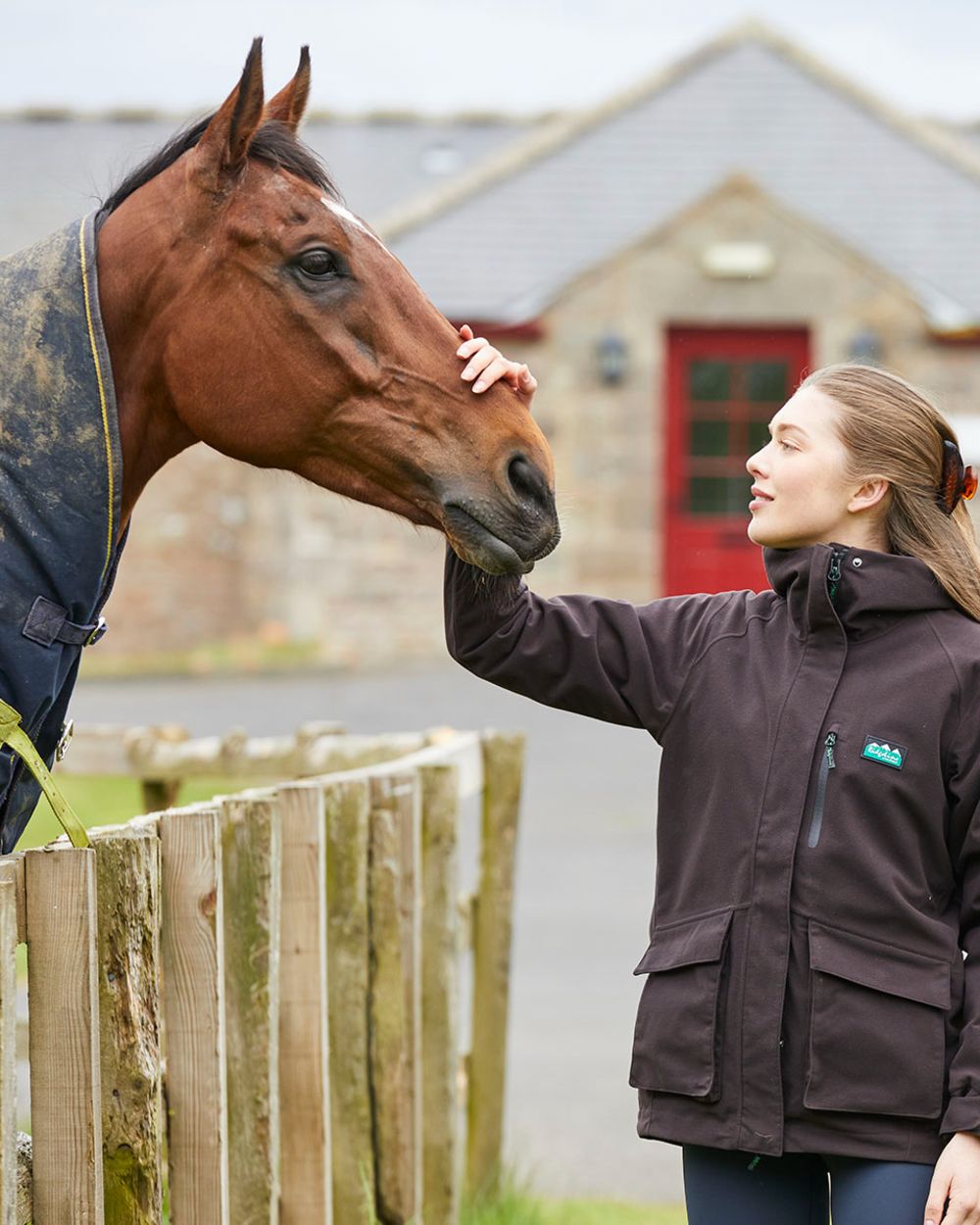Deep Bark coloured Ridgeline Ladies Rhea Jacket on farm background #colour_deep-bark