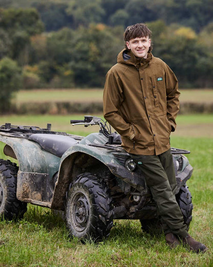 Teak coloured Ridgeline Mens Monsoon Light Jacket on farm background #colour_teak
