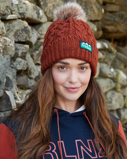Russet coloured Ridgeline Nordic Fleck Bobble Hat on rock background #colour_russet