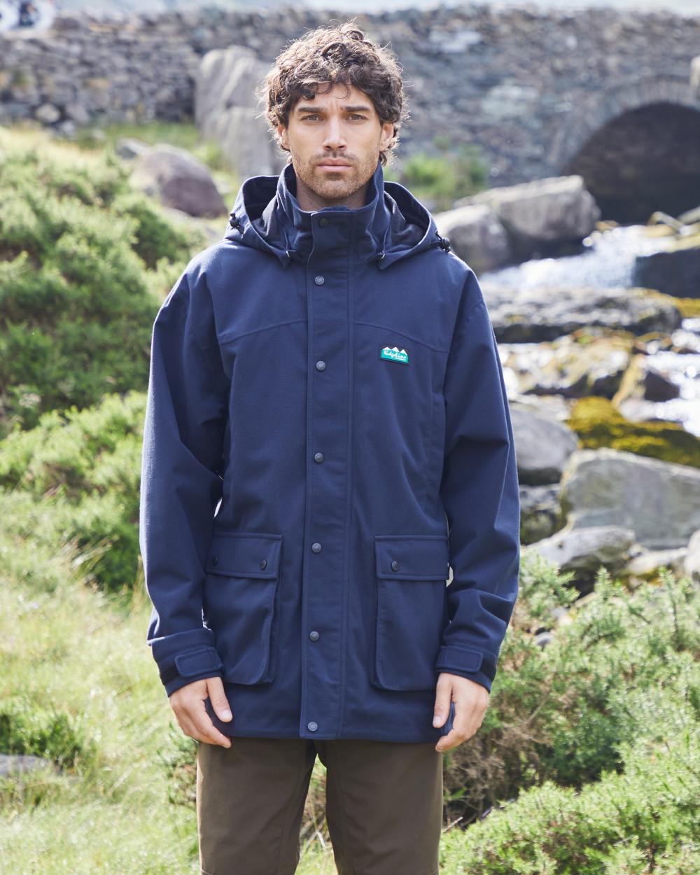 Navy coloured Ridgeline Torrent Waterproof Jacket on hilly background #colour_navy