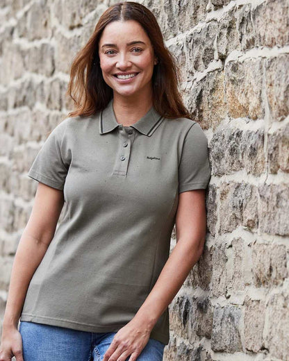 Smokey Olive coloured Ridgeline Womens Kilworth Polo Shirt on stone wall background #colour_smokey-olive