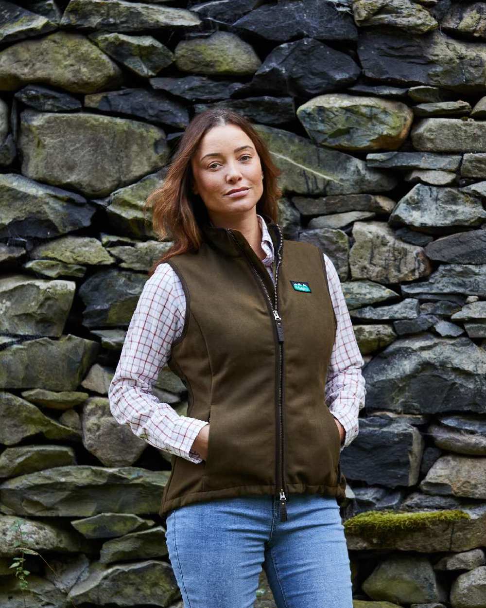 Teak coloured Ridgeline Womens Monarch Gilet on rock wall background #colour_teak